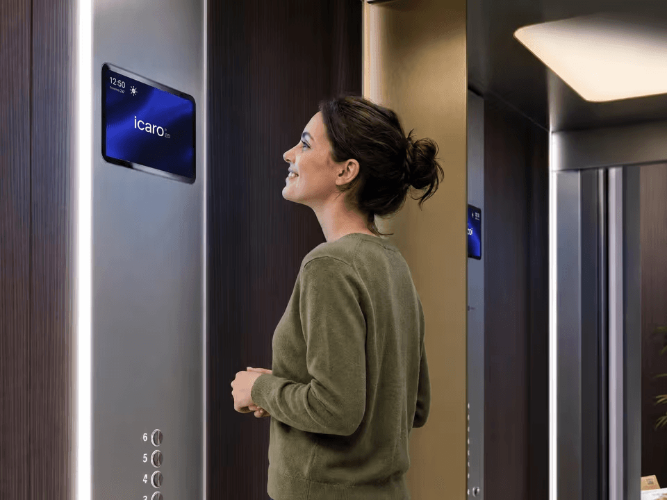 Mujer observando una pantalla digital Icaro Lift en un ascensor residencial